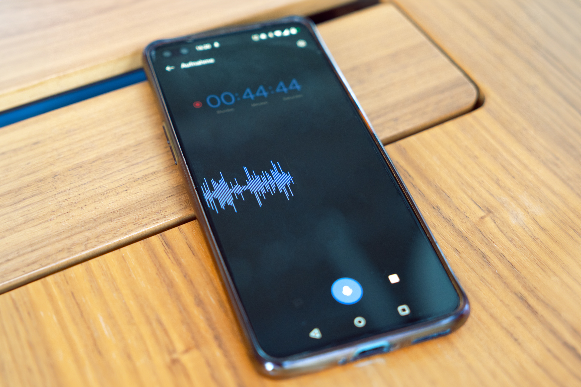 A cell phone is lying on the table. A recorder app is open, which has recorded a 44-minute and 44-second conversation