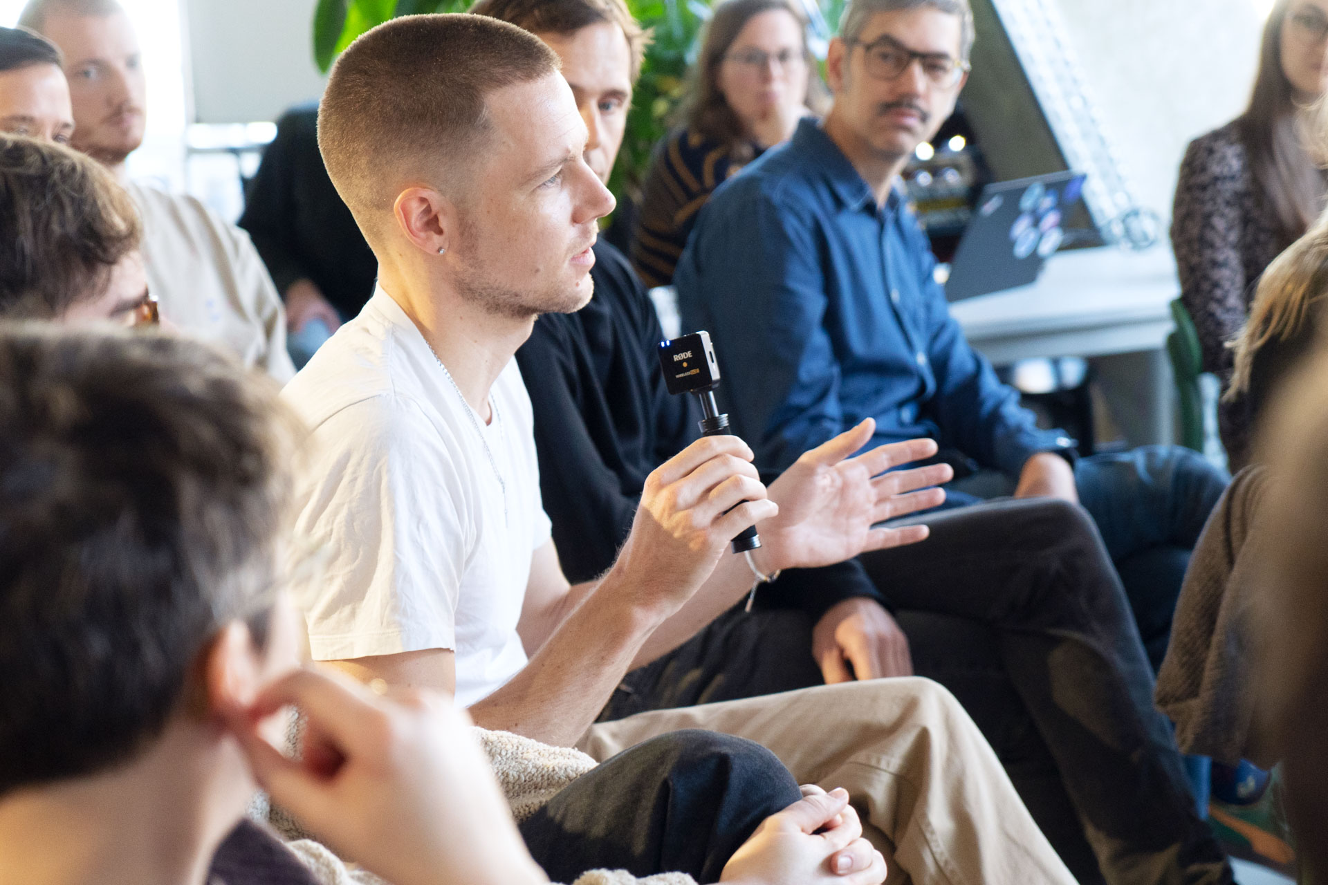 Mehrere Mitarbeitende des DigitalService sitzen aufgereiht auf Stühlen; ein MItarbeitender hat ein Mikrofon in der Hand und stellt eine Frage