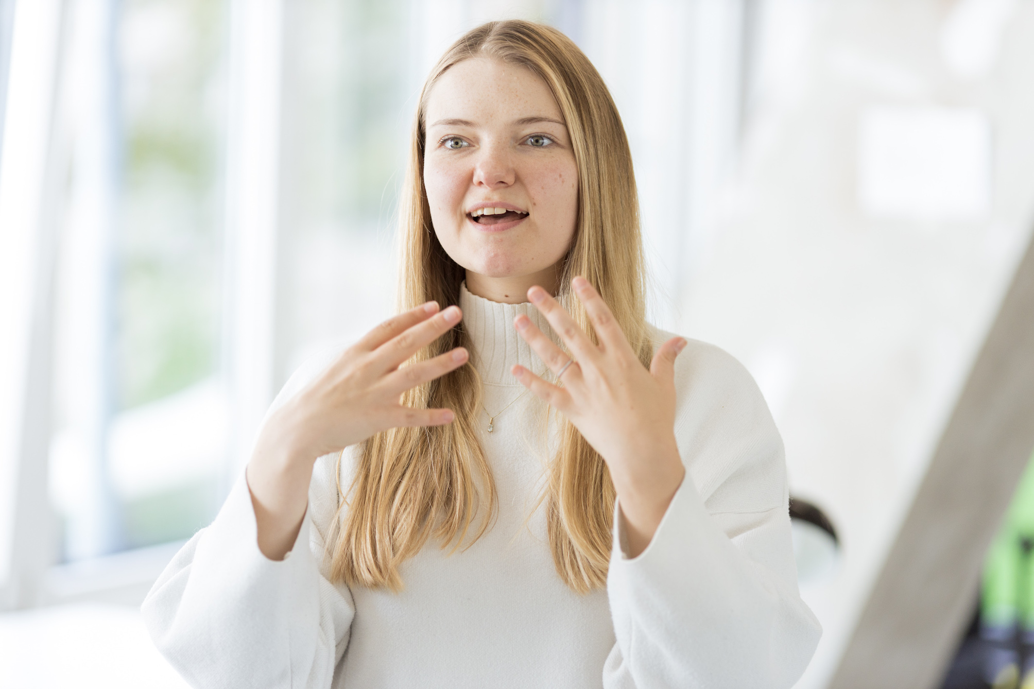 Carolin steht in den Büroräumen des DigitalService und gestikuliert mit beiden Händen auf Schulterhöhe während sie spricht