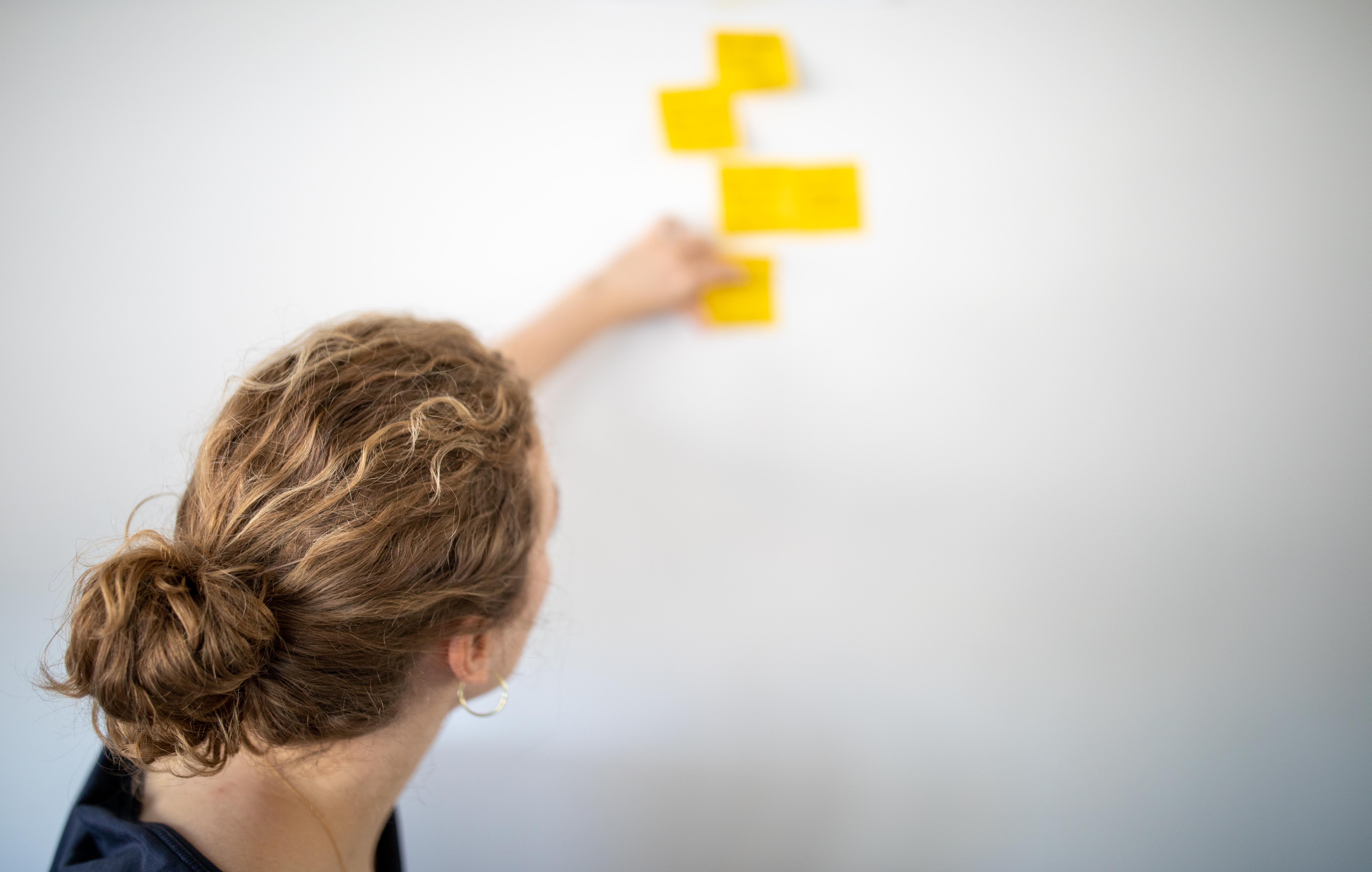 Frau befestigt einige Zettel an eine Wand.