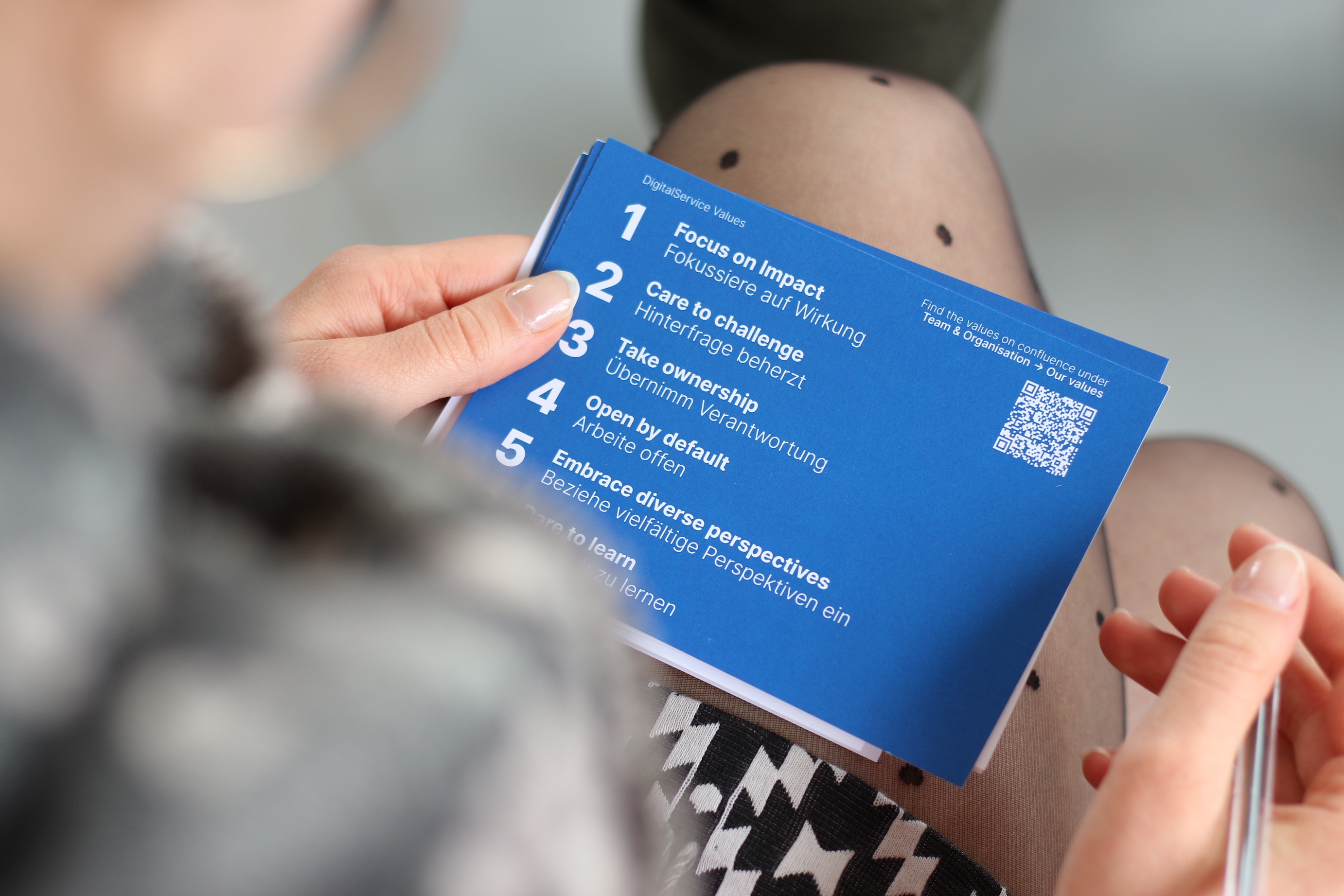 Auf einer blauen Karten stehen die sechs Werte des Digitalservice: 1. Fokussiere auf Wirkung. 2. Hinterfrage beherzt. 3. Übernimm Verantwortung. 4. Arbeite offen. 5. Beziehe vielfältige Perspektiven mit ein. 6. Trau Dich zu lernen.