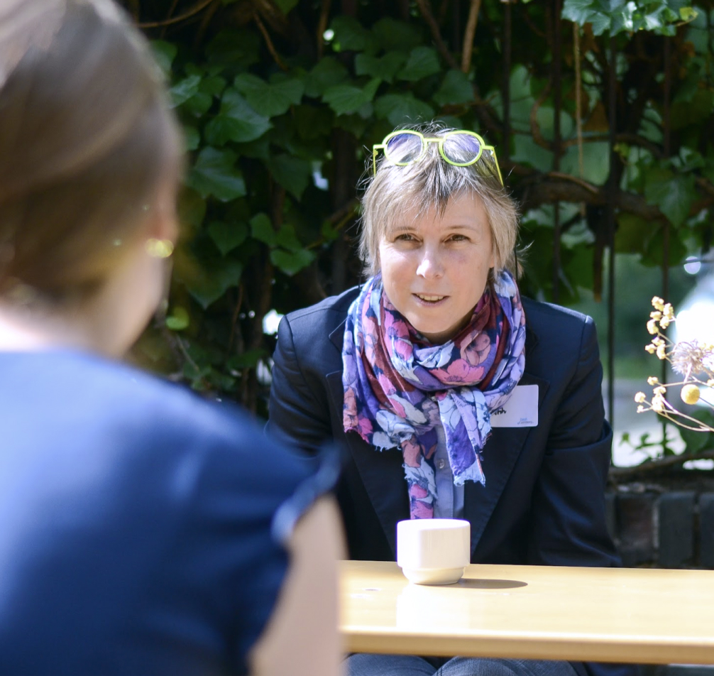 Zwei Frauen sitzen draußen an einem Tisch und sind im Gespräch