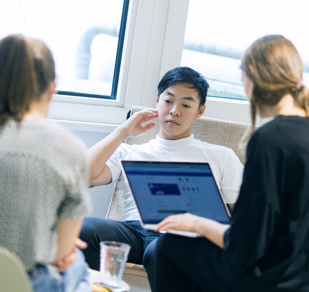 Drei Personen sitzen zusammen und arbeiten an Ideen