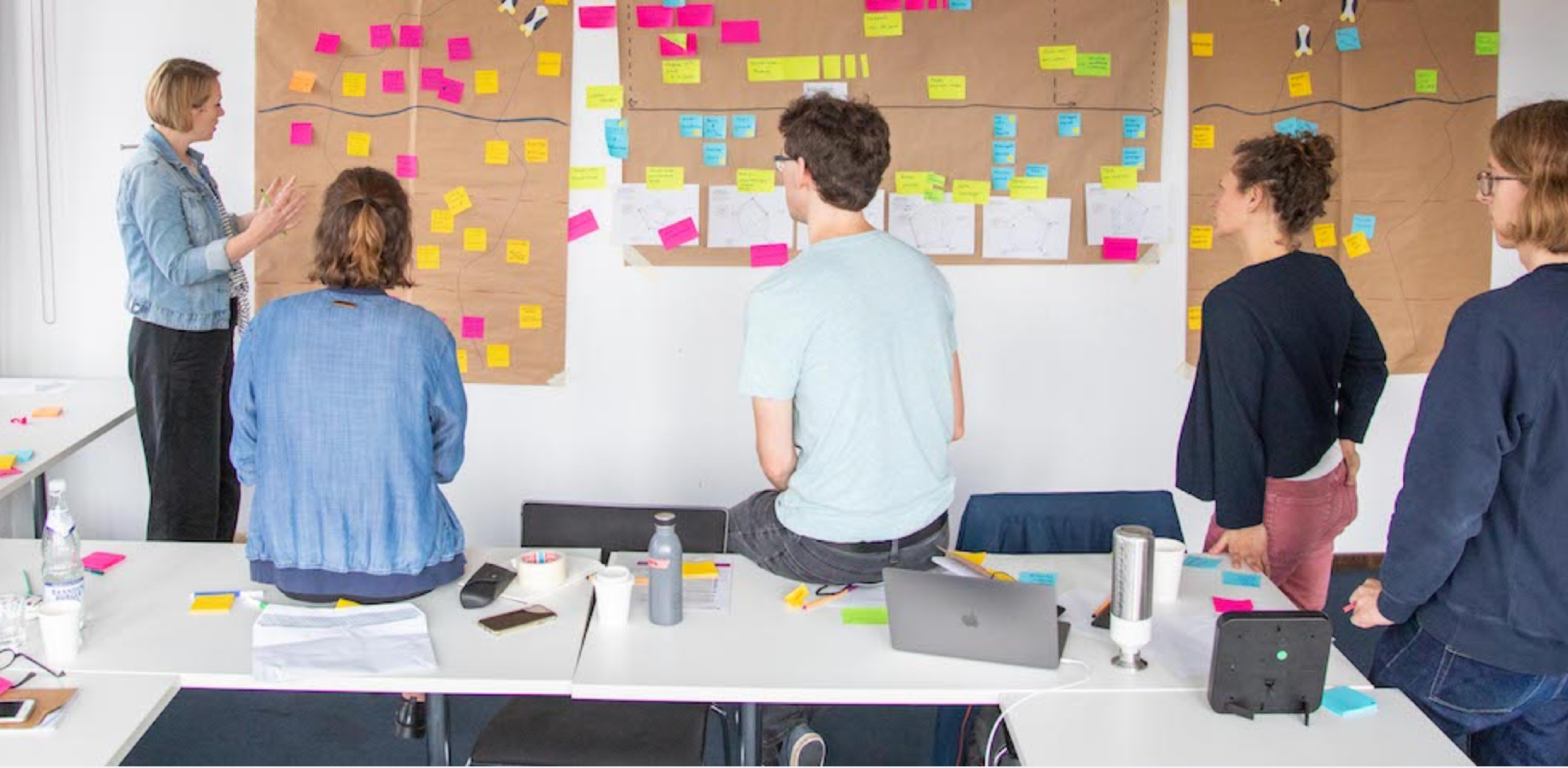 Personengruppe erarbeitet einem Plan an einer Wand mit Post-Its