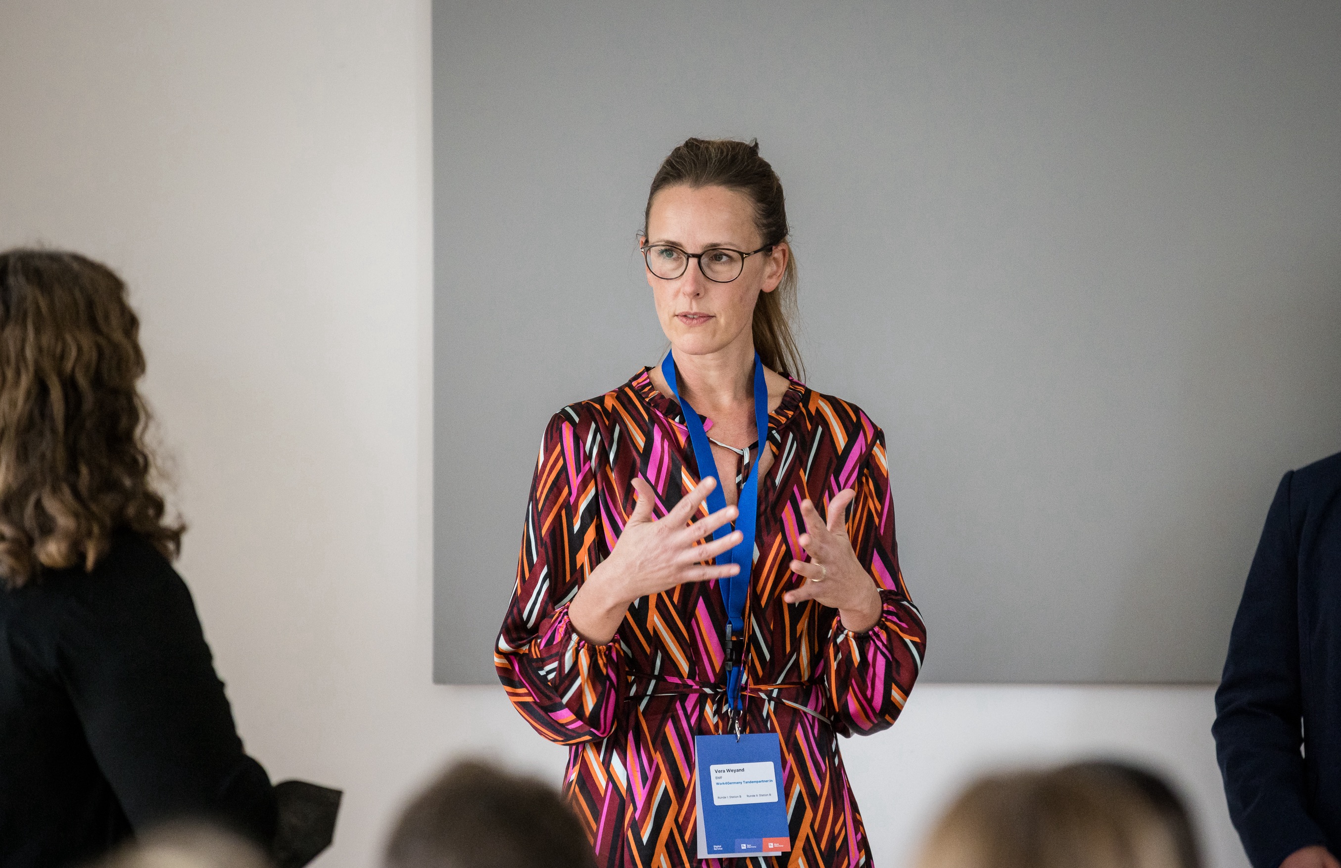 Portraitaufnahme einer ehemaligen Work4Germany Fellow, die gestikuliert und etwas präsentiert.