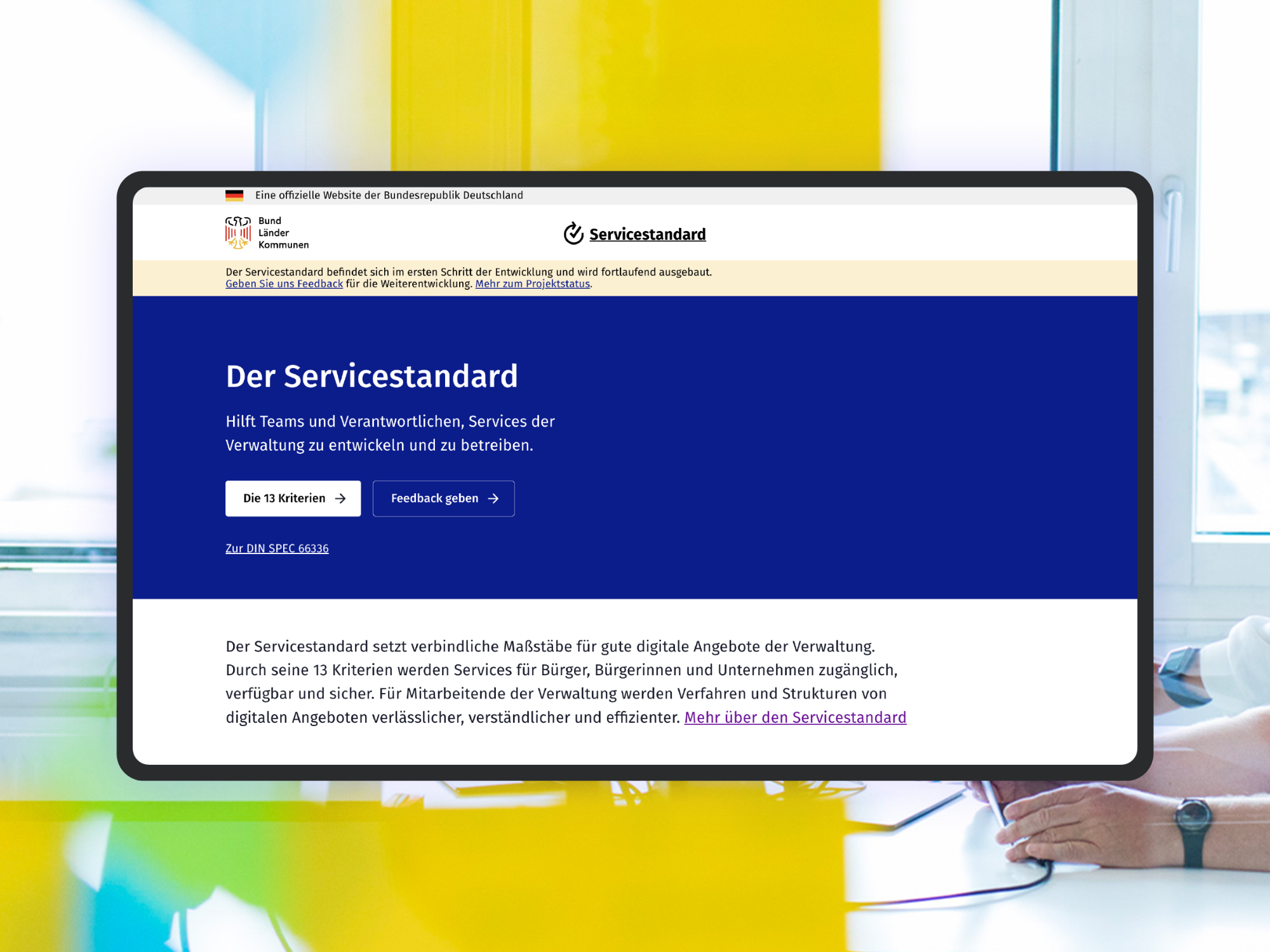 Ein Screenshot der aktuellen Beta-Version der Servicestandard Website; als visuelles Stilmittel sieht man im Hintergrund das Büro des DigitalService